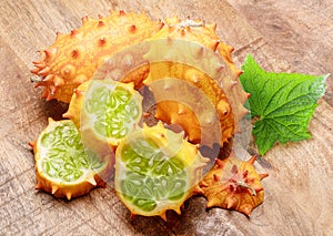 Kiwano fruit with kiwano slices on wooden background. Top view