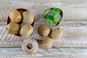 Kiwi in a bowl with dried slices, thread ball flat lay on a wooden background