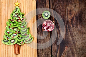 Kiwi Christmas tree - fun food idea for kids party or breakfast, New Year food on wooden background. Christmas tree food concept.