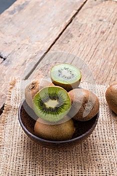 Kiwi fruit in a bowl on wooden background.