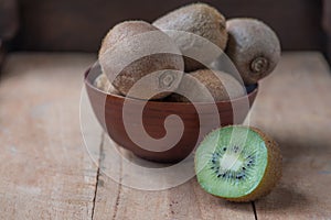 Kiwi fruit in a bowl on wooden background. Copy space