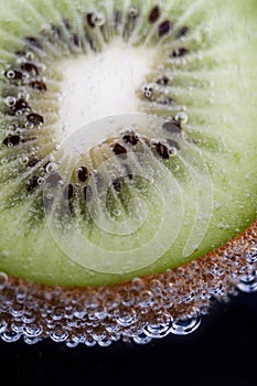 Kiwi fruit in carbonated water on a black backround