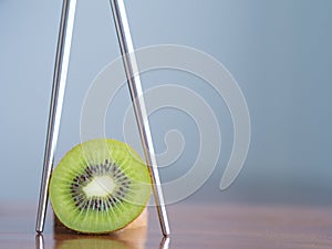 Kiwi fruit in chopsticks on a wooden table.