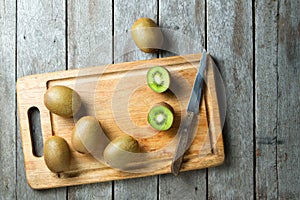 KIwi fruit on cutting board and knife on wooden background.