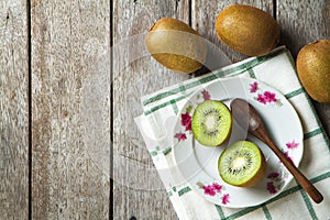 KIwi fruit on dish and spoon on wooden background.