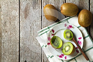 KIwi fruit on dish and spoon on wooden background.