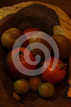 Kiwi fruit, Pomegranate and Indian Gooseberry fruit in wooden bowl in dark background. Healthy food