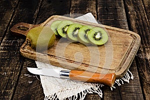 Kiwi fruit slice in cutting board have knife isolated on wood background