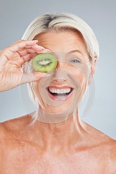 Kiwi, fruit and wellness of a senior woman with beauty skincare, health and a smile. Portrait of an happy elderly model