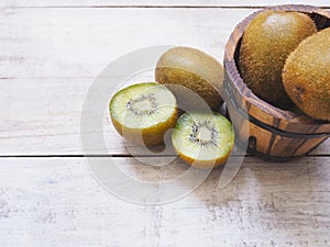 Kiwi fruits and barrel bucket on white wooden background.