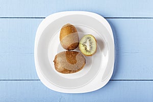 Kiwi fruits on white plate and on wooden blue table. Top view. Copy space