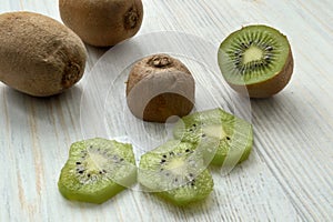 Kiwi fruits: whole and cut into slices, lie on a light-colored table