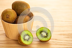 Kiwi fruits in a wooden bowl over wooden background with copy space