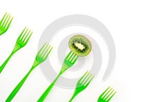 Kiwi and green forks in row on white background with copy spase