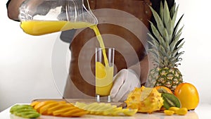 The kiwi, orange and lemons are cut into slices and placed near the orange fruit composition while the man is pouring