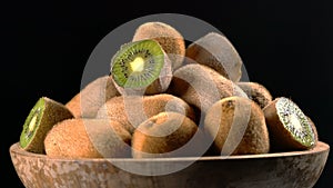 Kiwi in wooden bowl on black background