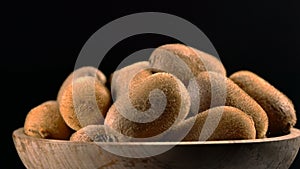 Kiwi in wooden bowl on black background