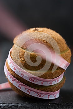 A kiwi wrapped by measuring tape expresses diet or healthcare