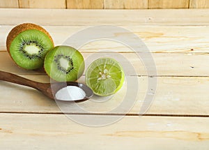 Kiwifruit and lemon with salt on wood cutting board