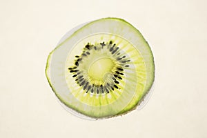 Kiwifruit slice closeup against an off white background