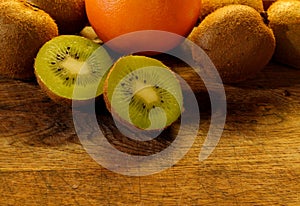 A kiwifruit split in half lies on a wooden cutting board