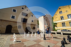 Klaipeda, Lithuania: Young cheerful woman and little girl hold chess pieces in their hands. Playing big chess on the