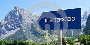 Klettersteig (via ferrata in German) sign post points towards a mountain.