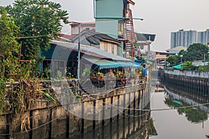 A klong or river channel with fishing boats, buildings and house fronts in Thailand