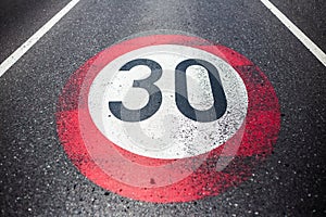 30km/h speed limit sign painted on asphalting road.