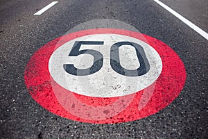50km/h speed limit sign painted on asphalting road.