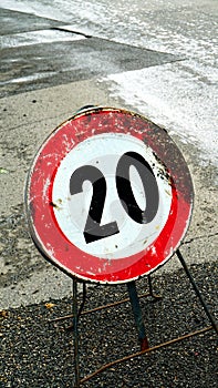 20km speed limit construction site sign, damaged by time on asphalt photo