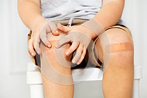 Knee of a boy with patch, focus on hands touch scratch