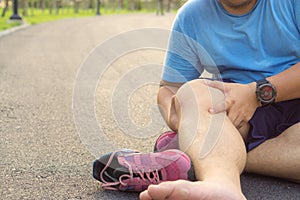 Knee Injuries. Fat man holding knee with his hands in pain after suffering muscle injury during a running workout at park.