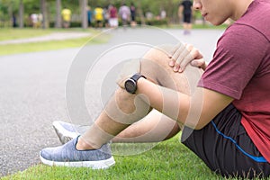 Knee Injuries. Young sport man holding knee with his hands in pain after suffering muscle injury during a running workout at park