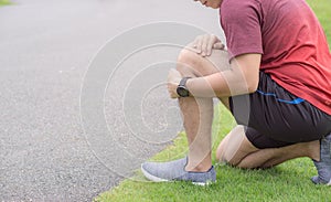 Knee Injuries. Young sport man holding knee with his hands in pain after suffering muscle injury during a running workout at park