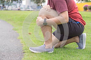 Knee Injuries. Young sport man holding knee with his hands in pain after suffering muscle injury during a running workout at park