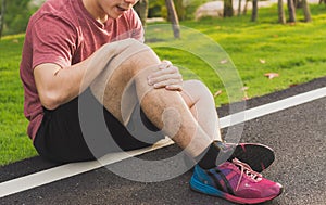 Knee Injuries. Young sport man holding knee with his hands in pain after suffering muscle injury during a running workout at park