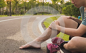 Knee Injuries. Young sport man holding knee with his hands in pain after suffering muscle injury during a running workout at park