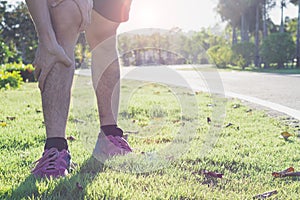 Knee Injuries. Young sport man holding knee with his hands in pain after suffering muscle injury during a running workout at park