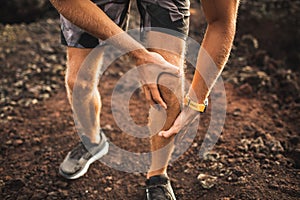 Knee injury on running outdoors. Man holding knee