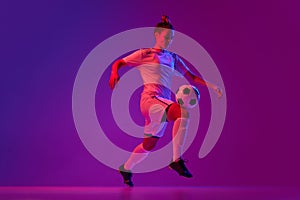 Knee kick. Young professional female football, soccer player in motion, training, playing over gradient pink background
