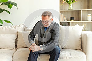 Knee pain arthritis body sick health care concept. Unhappy middle aged senior man suffering from knee ache sitting on