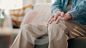 Knee pain, hands and closeup of senior man on a sofa with muscle, cramps or inflammation in his home. Zoom, legs and