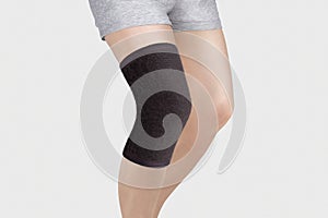 Knee Support Brace on leg isolated on white background. Orthopedic Anatomic Orthosis. Braces for knee fixation, injuries and pain.