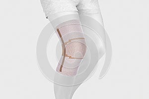 Knee Support Brace on leg isolated on white background. Orthopedic Anatomic Orthosis. Braces for knee fixation, injuries and pain.