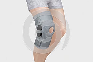Knee Support Brace on leg isolated on white background. Orthopedic Anatomic Orthosis. Braces for knee fixation, injuries and pain.