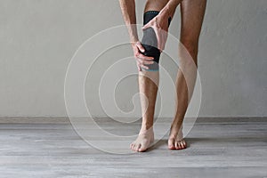 Knee Support Brace on male leg on grey background. Elastic orthopedic orthosis. Anatomic braces for knee fixation