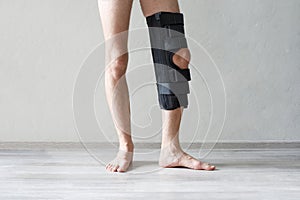 Knee support brace on a male leg. Man in an orthosis. Orthopedic anatomic braces for knee fixation, injuries and pain.