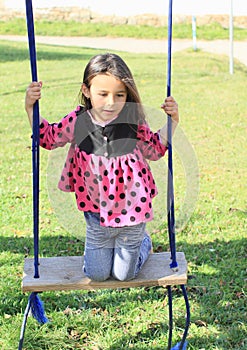 Kneeing girl on swing