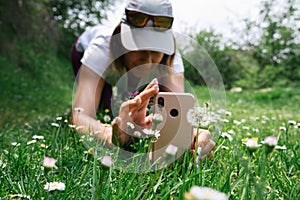 Kneeling female hiker photographing a dandelion plant